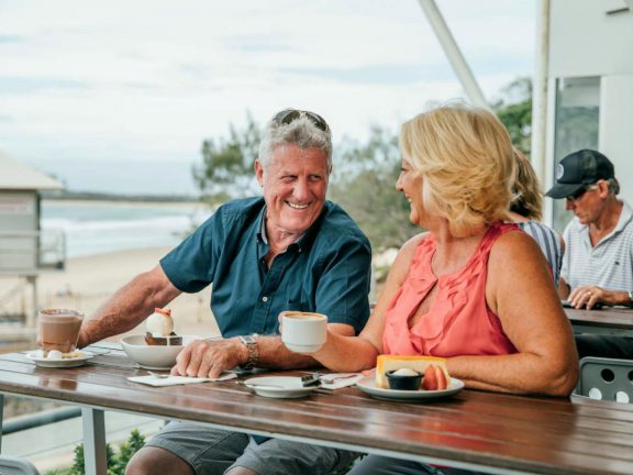 mooloolaba-surf-club-elderly-couple-on-deck-next-to-beach-drinking-coffee