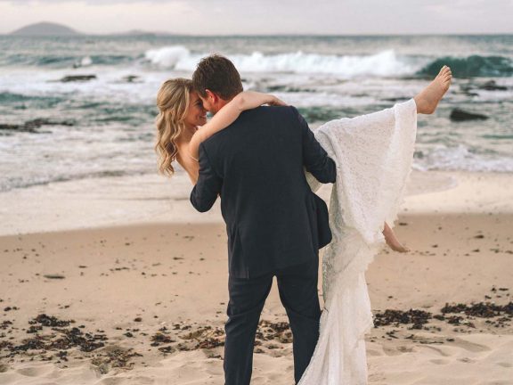 mooloolaba-surf-club-wedding-groom-holding-bride-on-beach